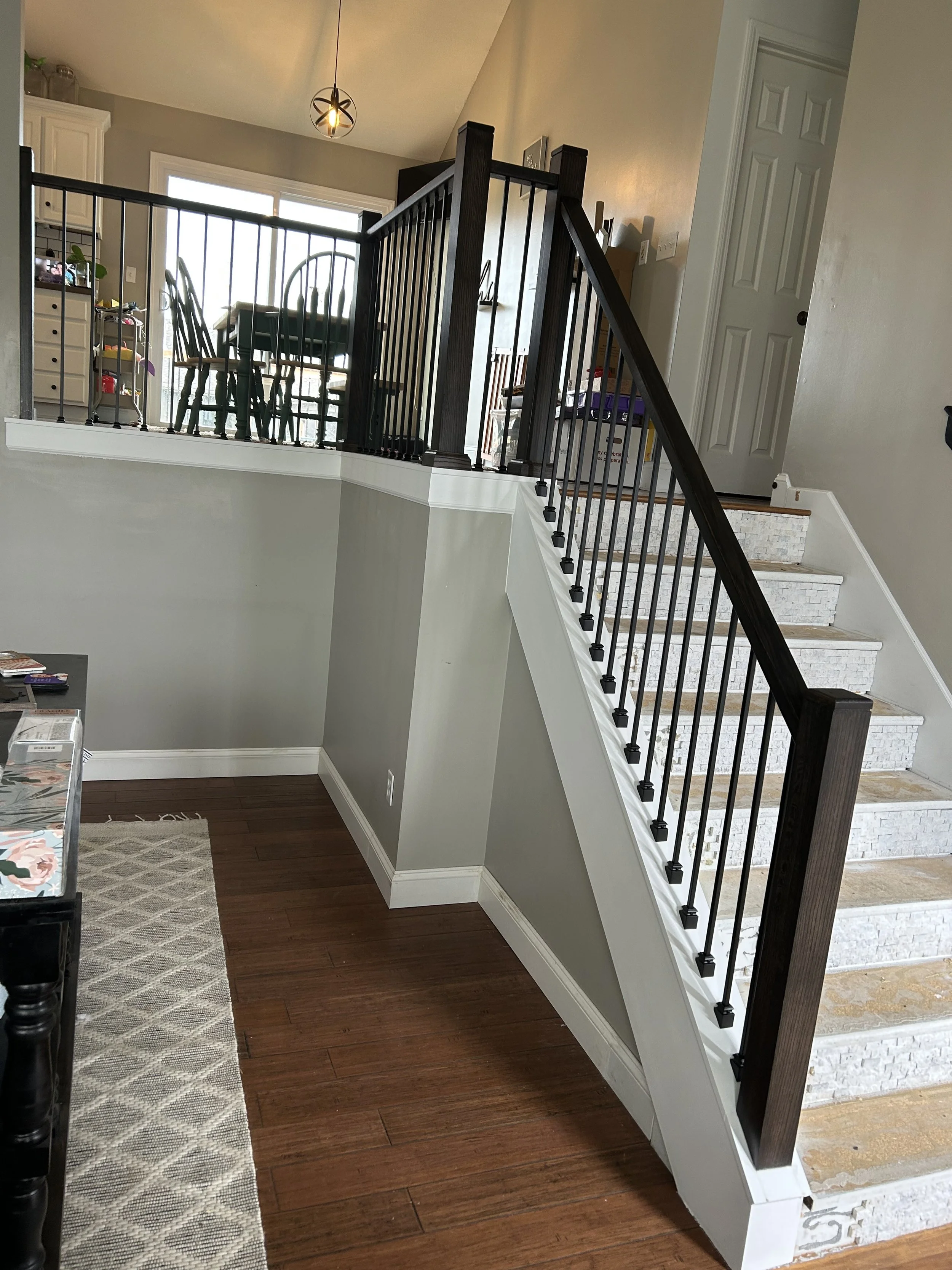 Finished staircase with black iron balusters and handrail