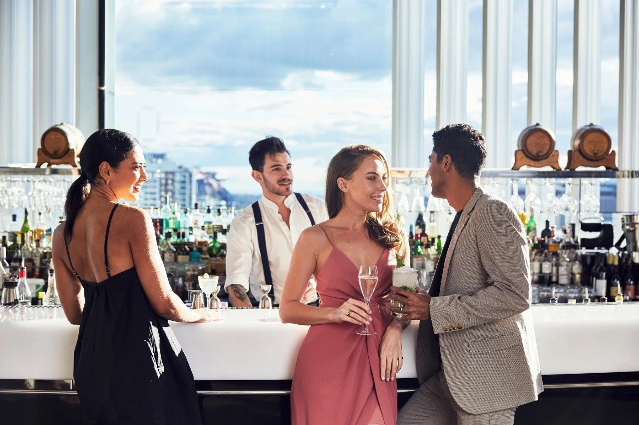 People dressed in formal clothes standing at a bar smiling