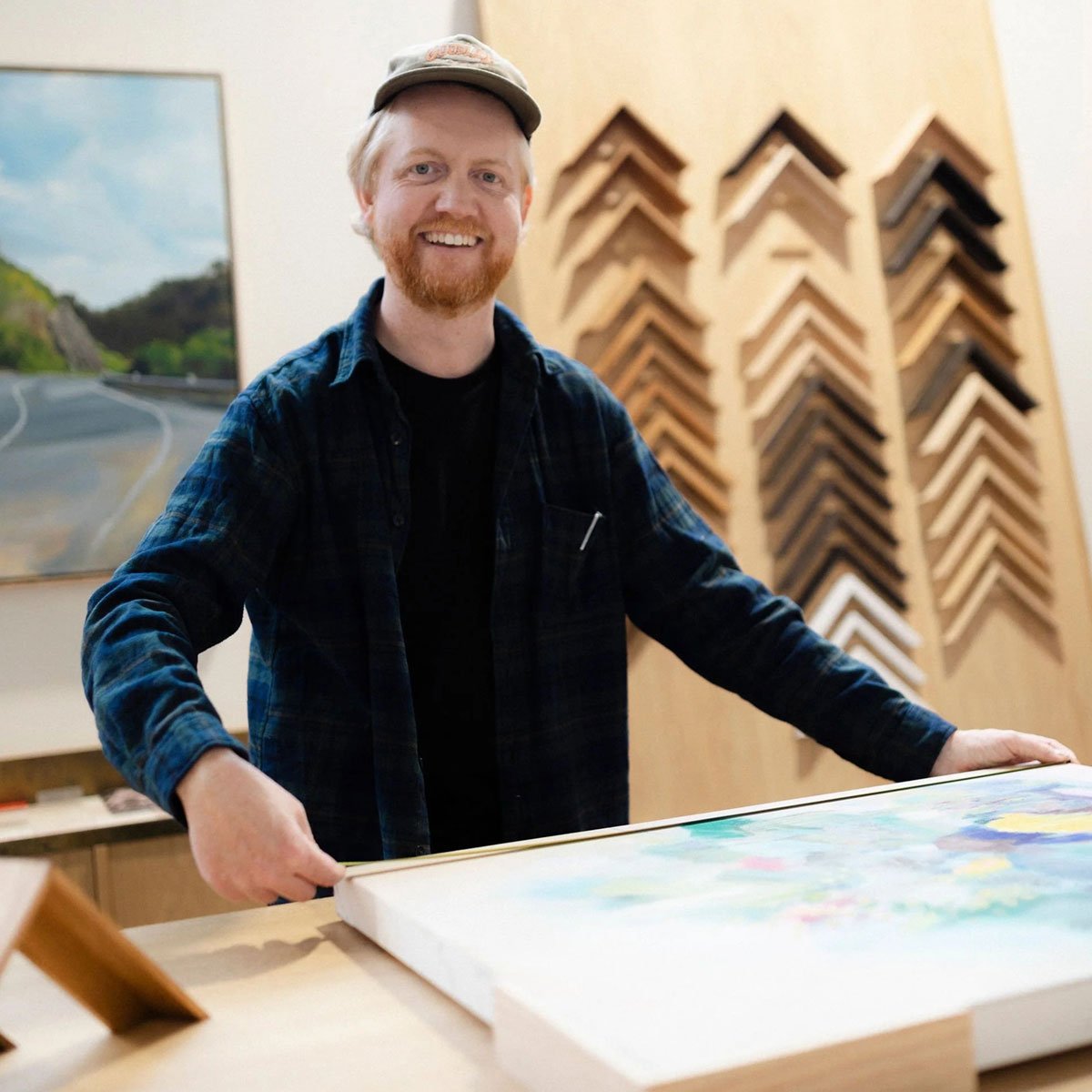 Tom, the picture framer, holding an artwork in the workshop