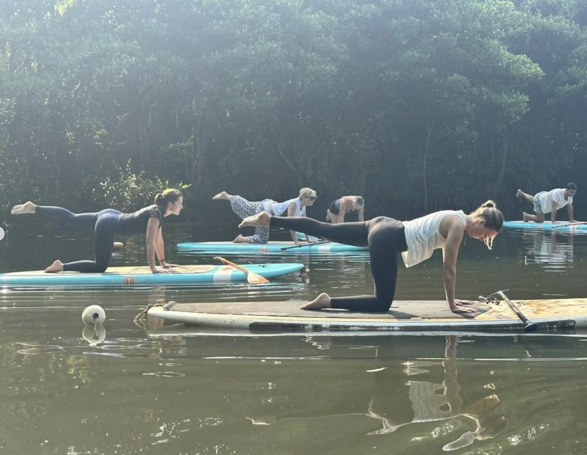Zoe from Yoga with Zoe Lee guiding a SUP yoga session on the water during the Sri Lanka retreat.