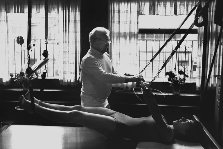 Joseph Pilates NEW YORK - OCTOBER 1961: Joe Pilates, Inventor, physical fitness guru and founder of the Pilates exercise method instructs a client on the Cadillac and works her through an exercise routine in his 8th Avenue studio on October 4, 1961 in New York City, New York. (Photo by I.C. Rapoport/Getty Images)