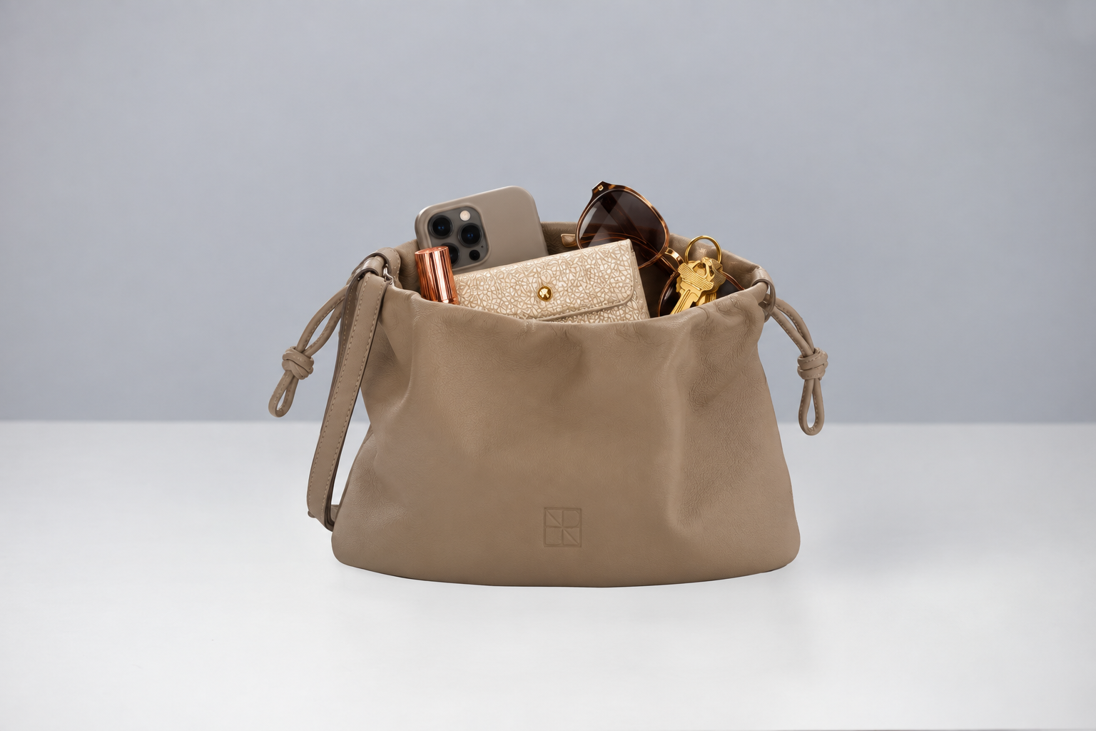 Offene taupefarbene Tasche mit fünf Essentials.png