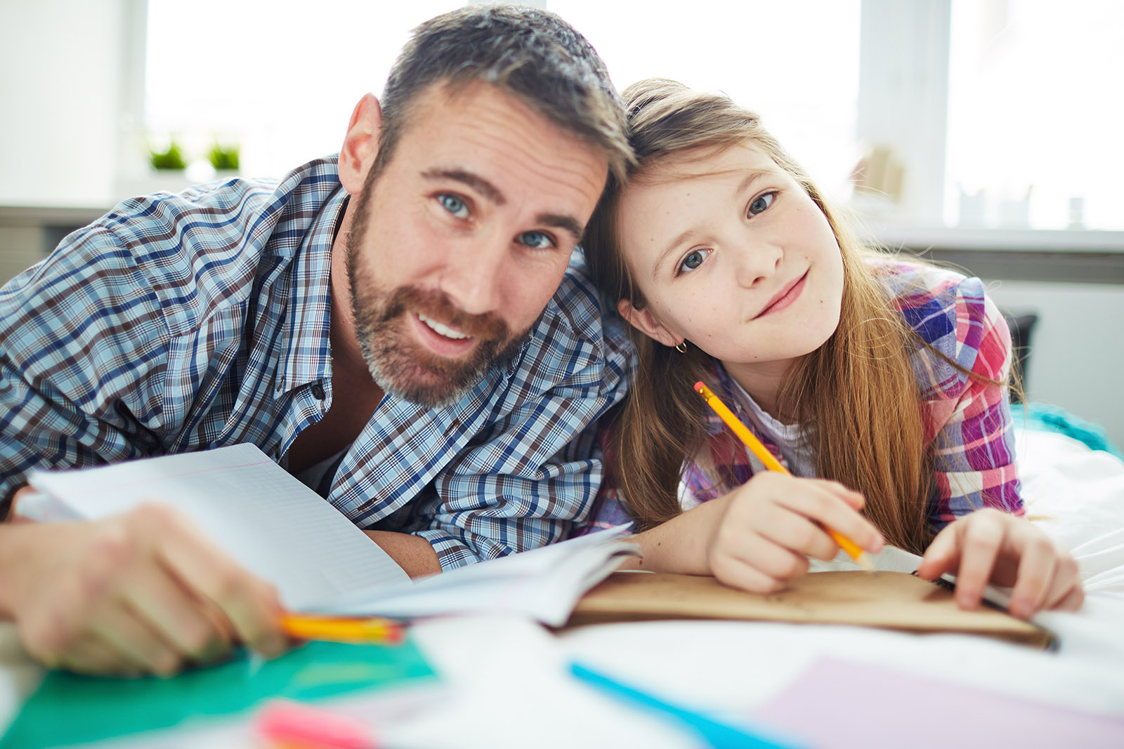 Father and daughter writing on book 