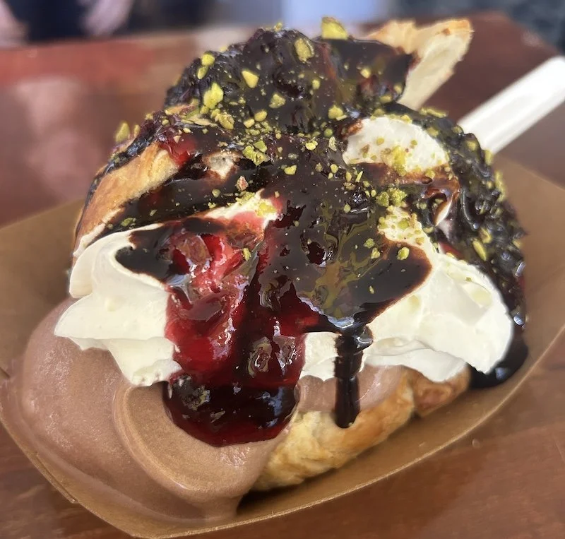 croissant with gelato, whipped cream, chocolate, cherry sauce and pistachios