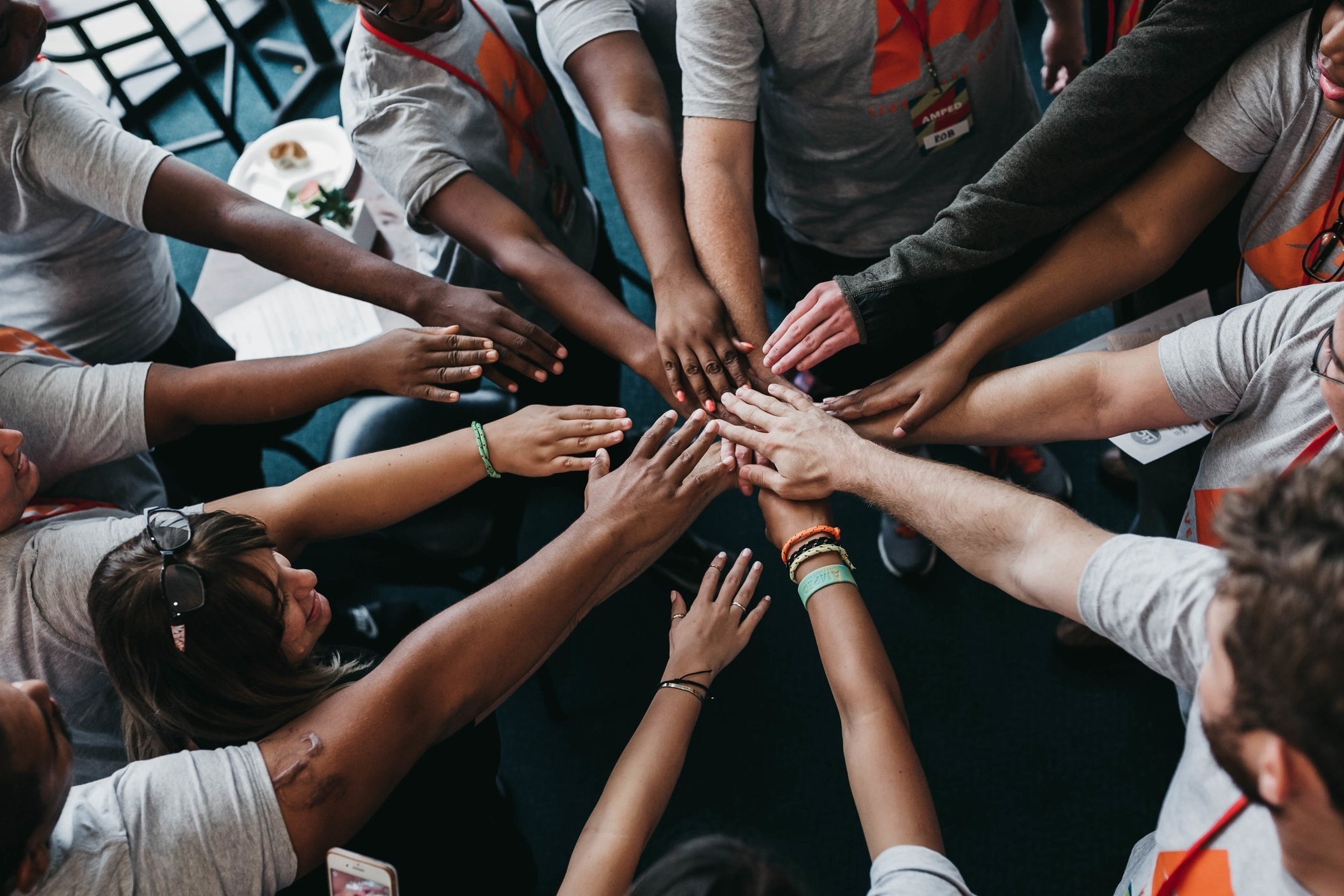 Group of diverse people placing their hands together in a circle, showing unity and teamwork.