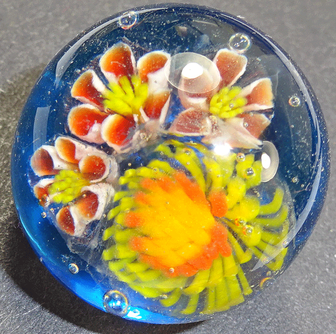 Glass paperweight button with flowers on blue