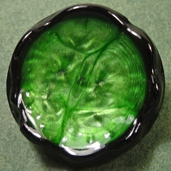 Vintage black glass button with green swirly glaze