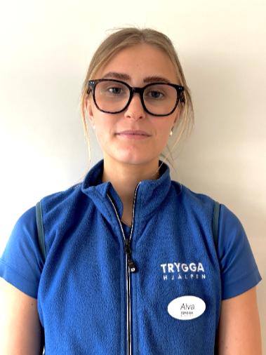 Person wearing a blue polo shirt with logos, light background.