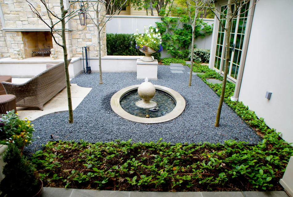 View of finial fountain to show exact lines with pedestal planter of seasonal color. Blackstar gravel and and Sandy Leaf Fig Ivy frame the space.