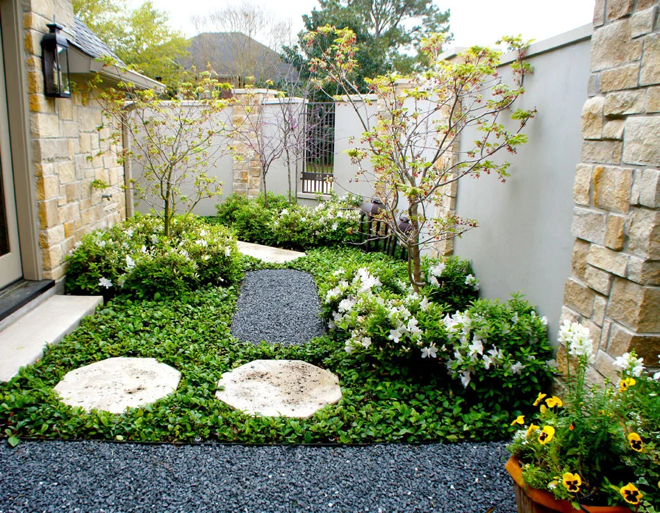 View of the secret side yard from under the pergola. Blooming white azaleas add in informal element to this otherwise formal French garden.