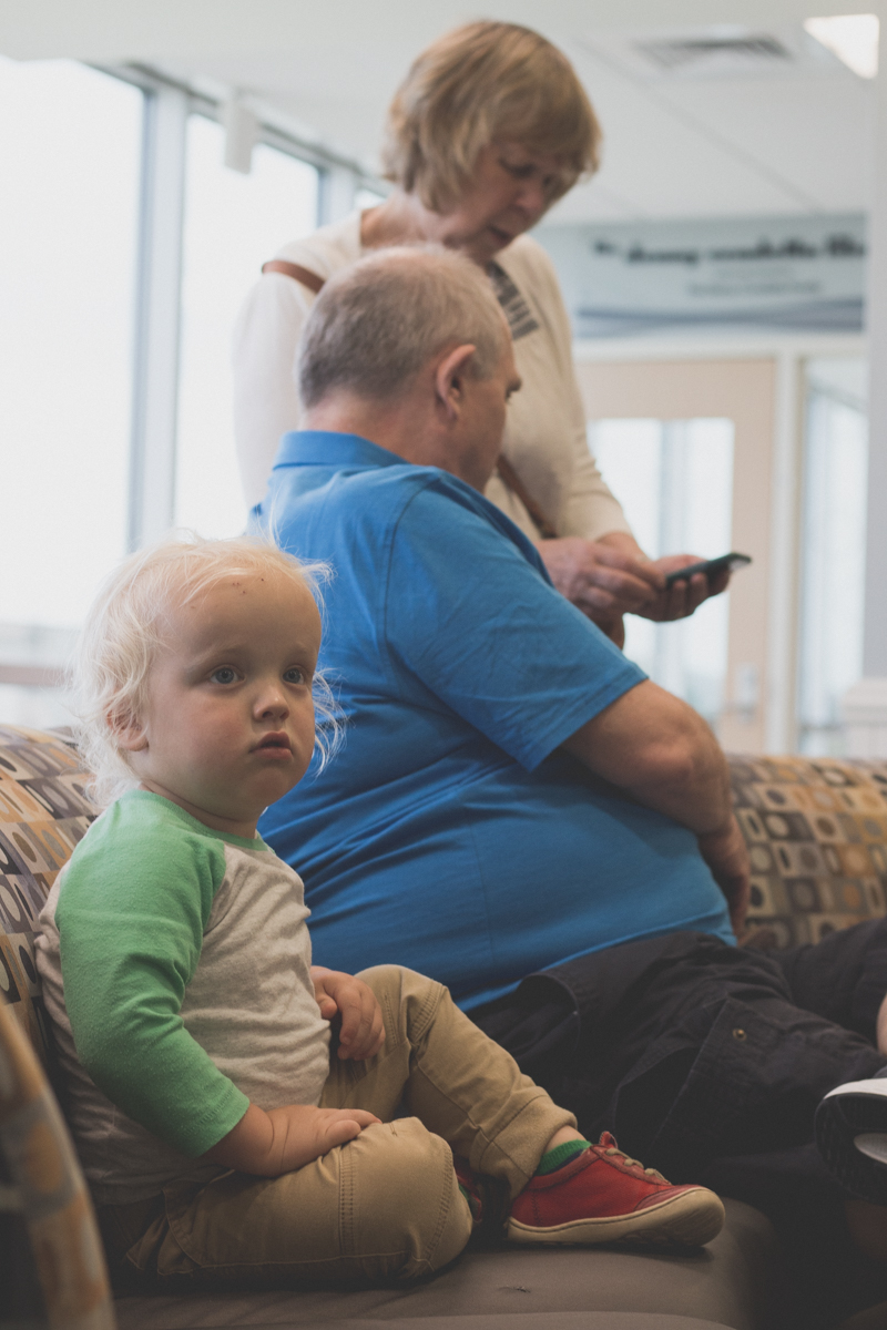 Boy sitting with middle-age seniors in waiting room.