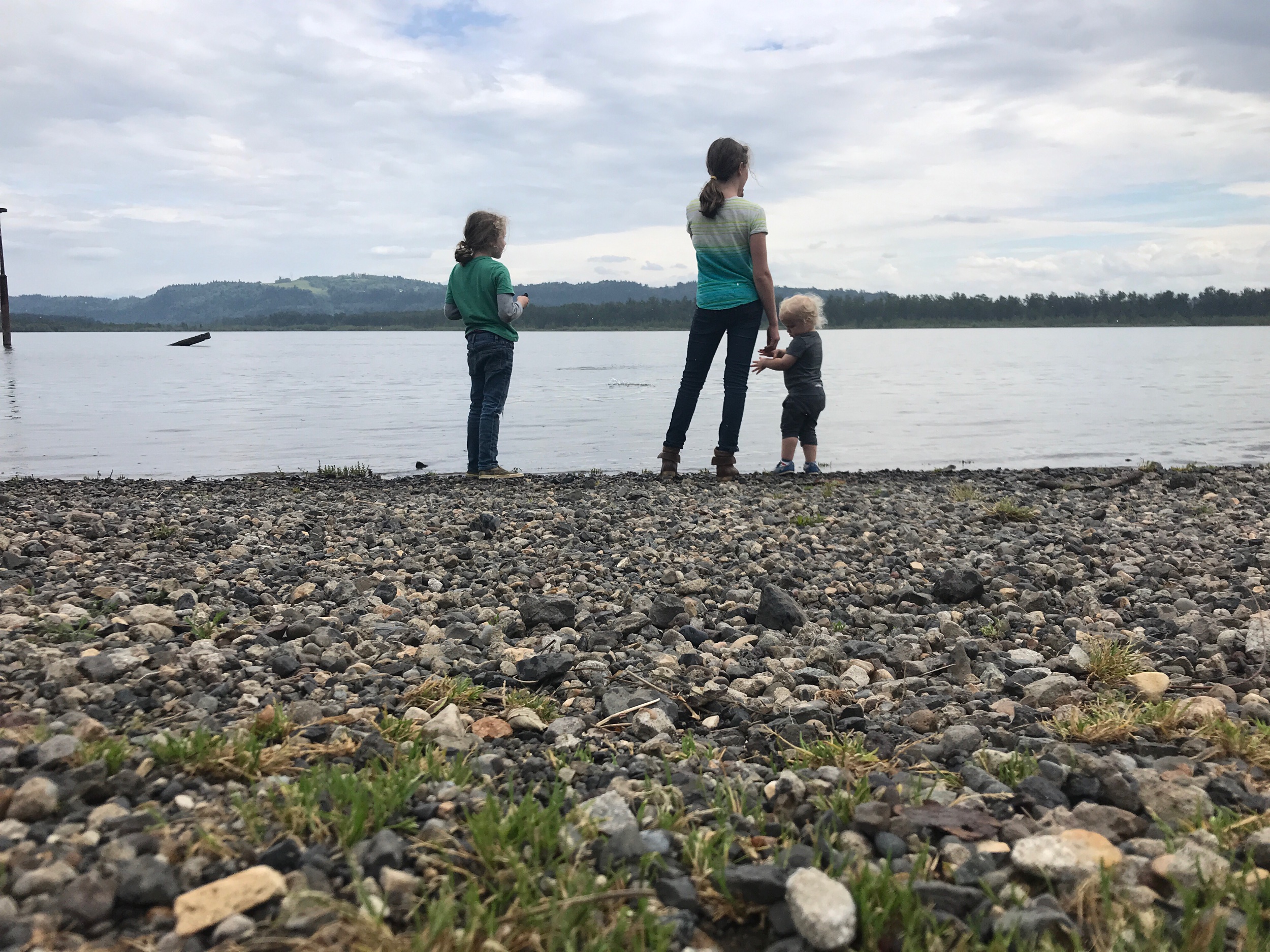 Children standing the edge of the Columbia River throwing rocks 