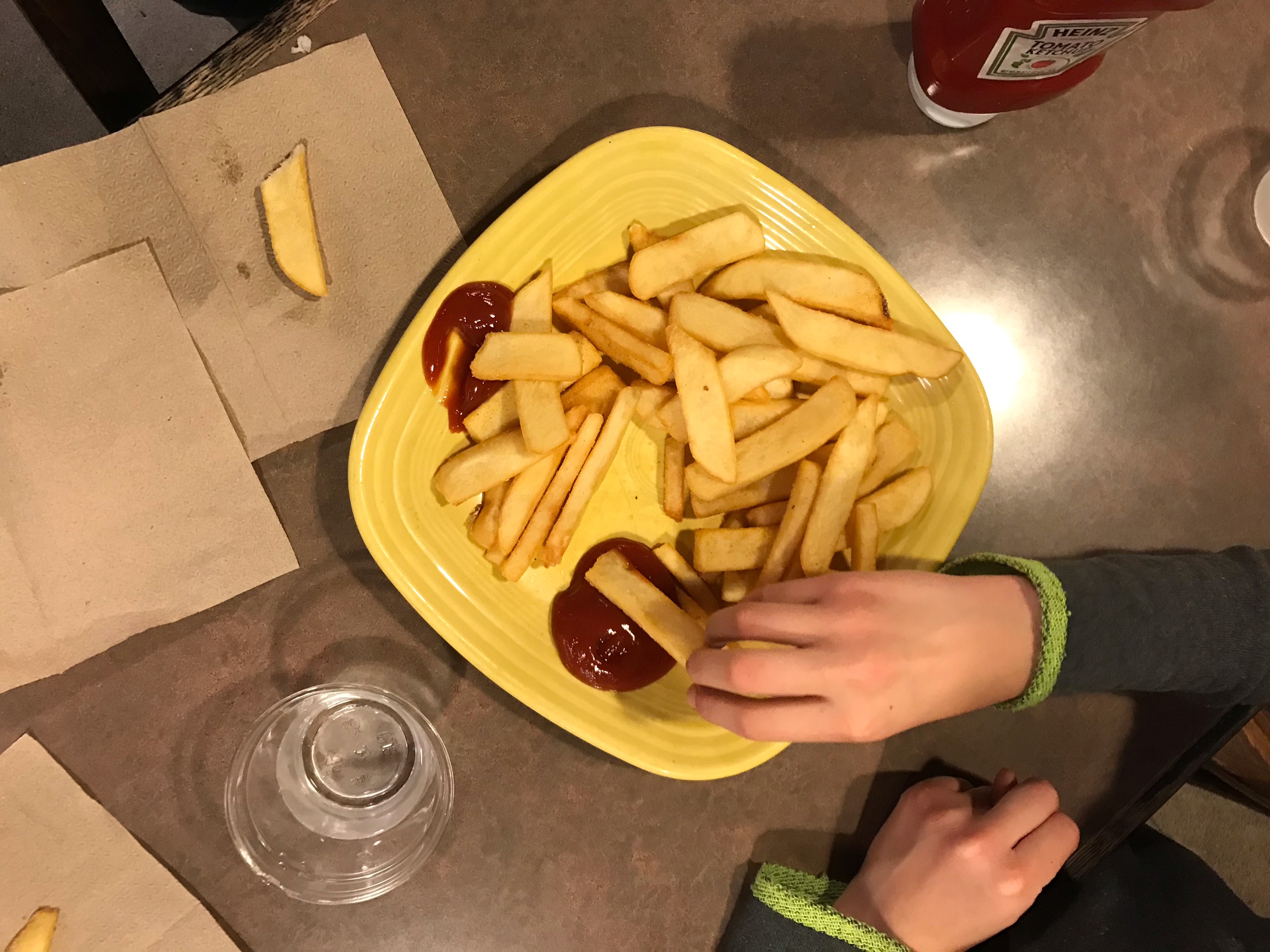 Overhead view of small children eating a huge plate of French fries.