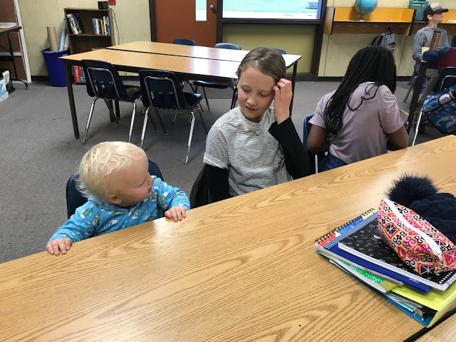 Toddler boy sits with his 6th grade sister in a classroom.jpg