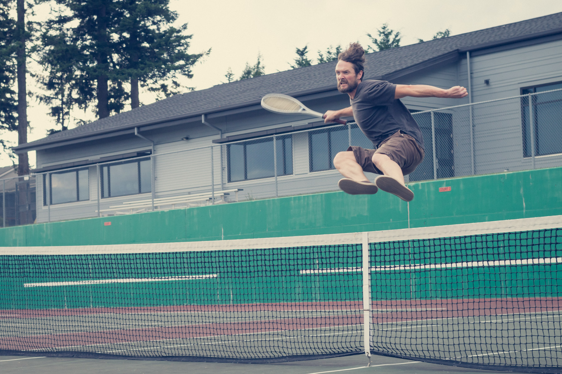 42-year old bearded male with grimace on his face attacks the net aggressively as he plays a quiet tennis match with his young children. (photo: M.D. Long)