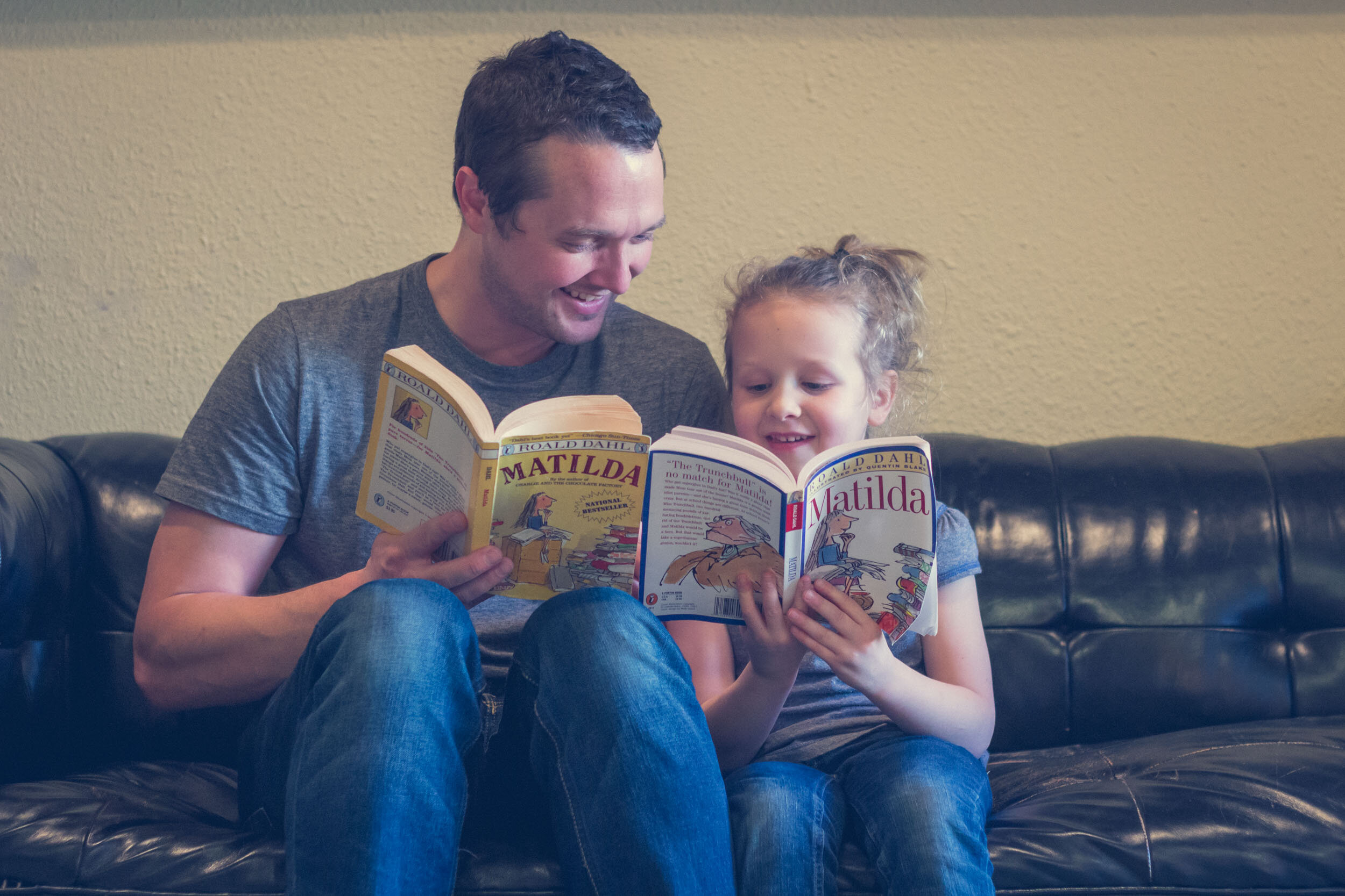 Dad and his daughter reading two different copies of "Matilda"