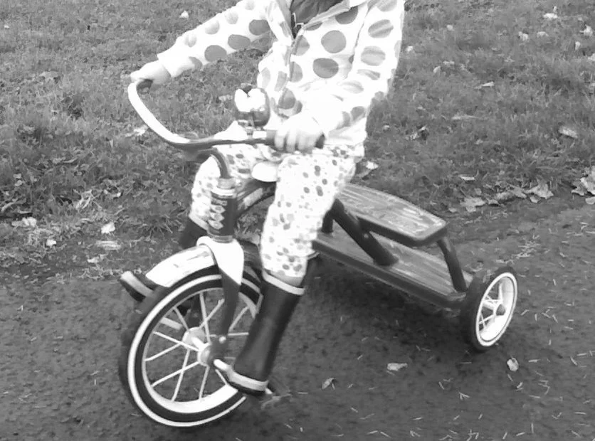 2-year old girl riding tricycle (head is cropped)