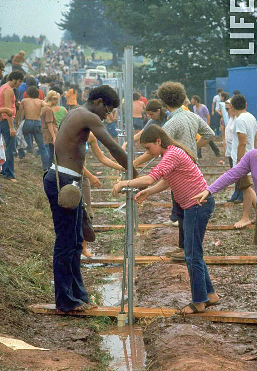 Festival-goers-standing-at-water-pump-trying-to-get-water-during-a-day-at-Woodstock-1969.jpg