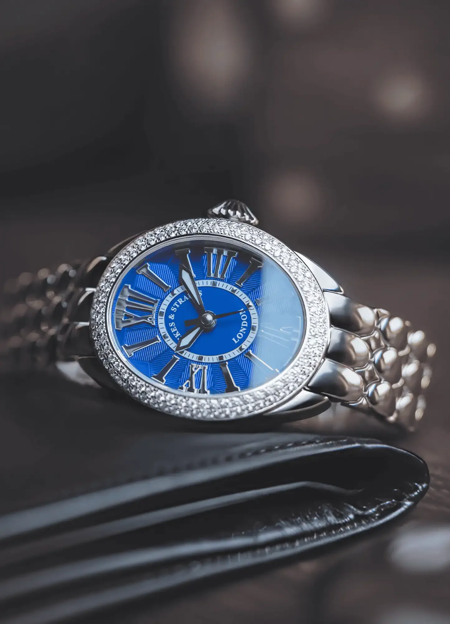 Regent 3643 ladies watch on the leather surface with blue dial, diamond bezel, and sleek steel bracelet.webp