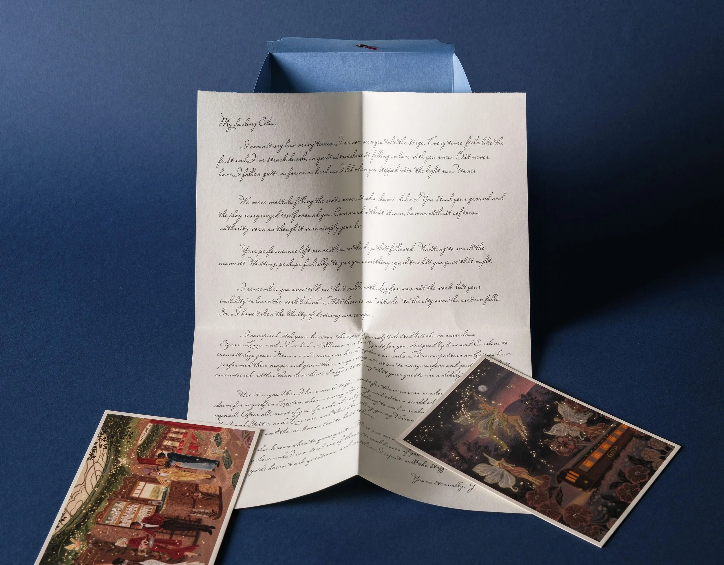 Open greeting card with handwritten message on blue background, with photographs of Christmas decorations and a festive scene at the bottom.