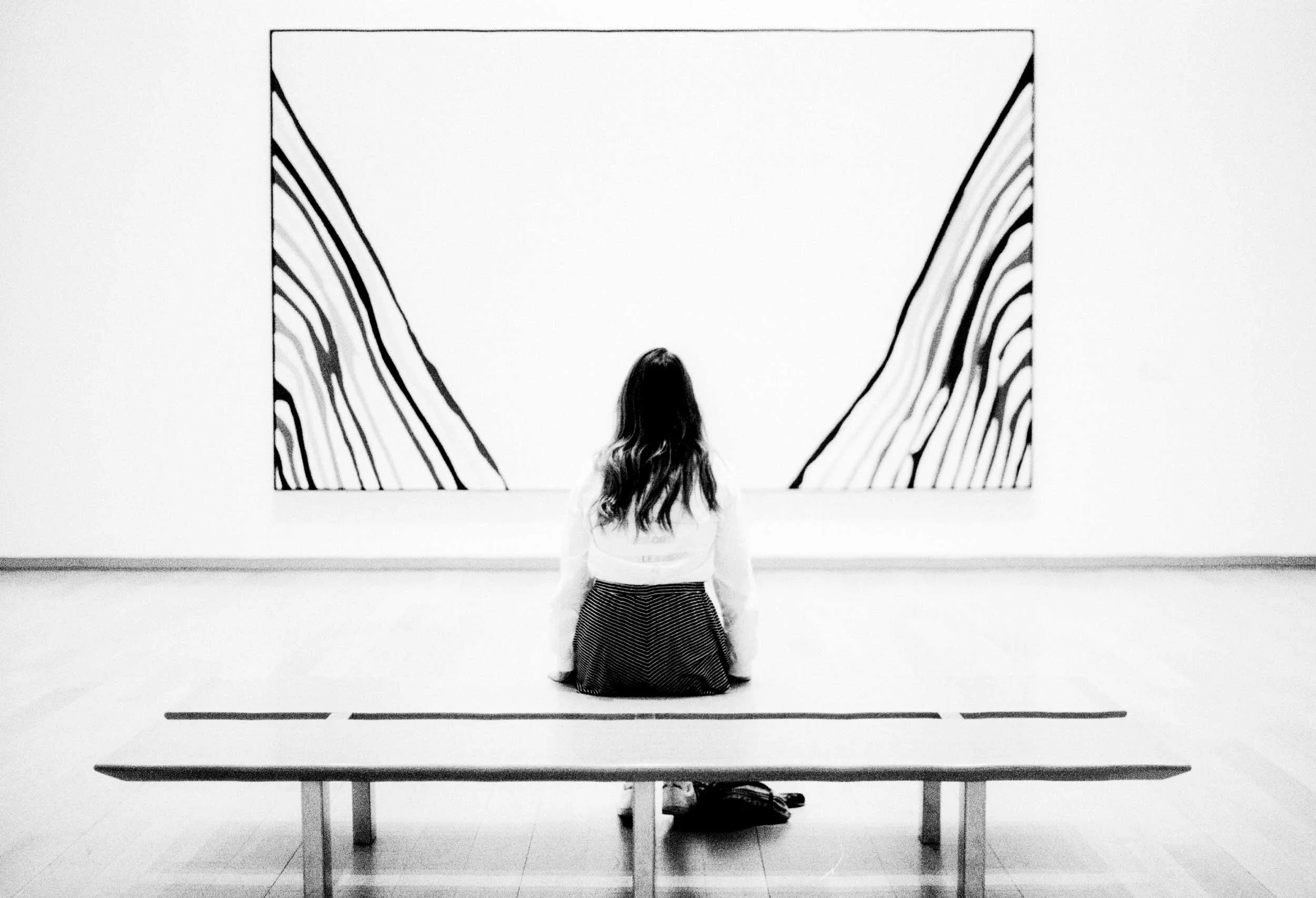 Woman sitting in gallery looking at painting