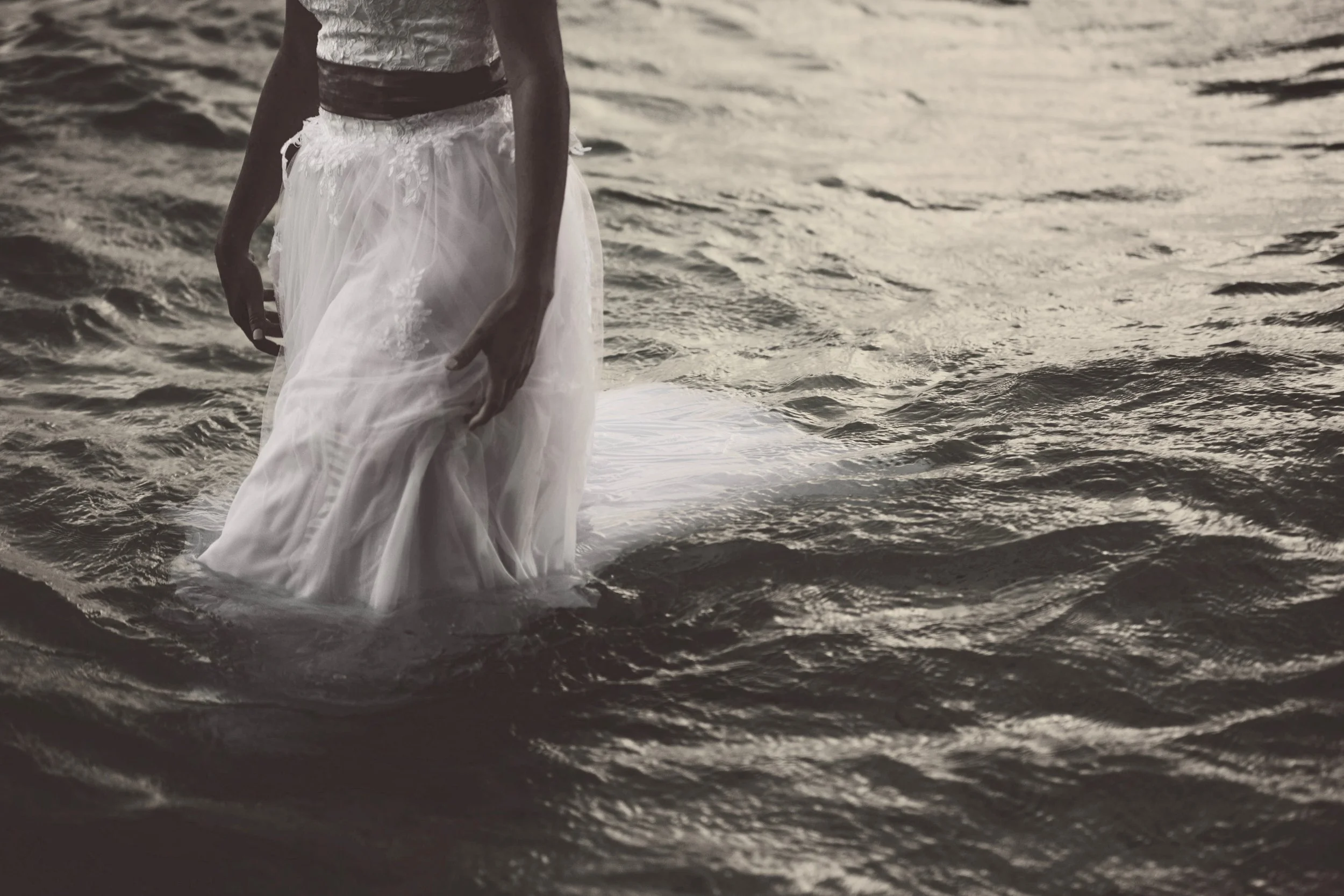 Person standing in water wearing a white dress