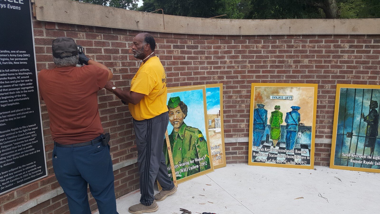  Artist Napolean Hill (right) is assisted in installing his completed mural panels.  Photo courtesy of Dr. Ervin Griffin  