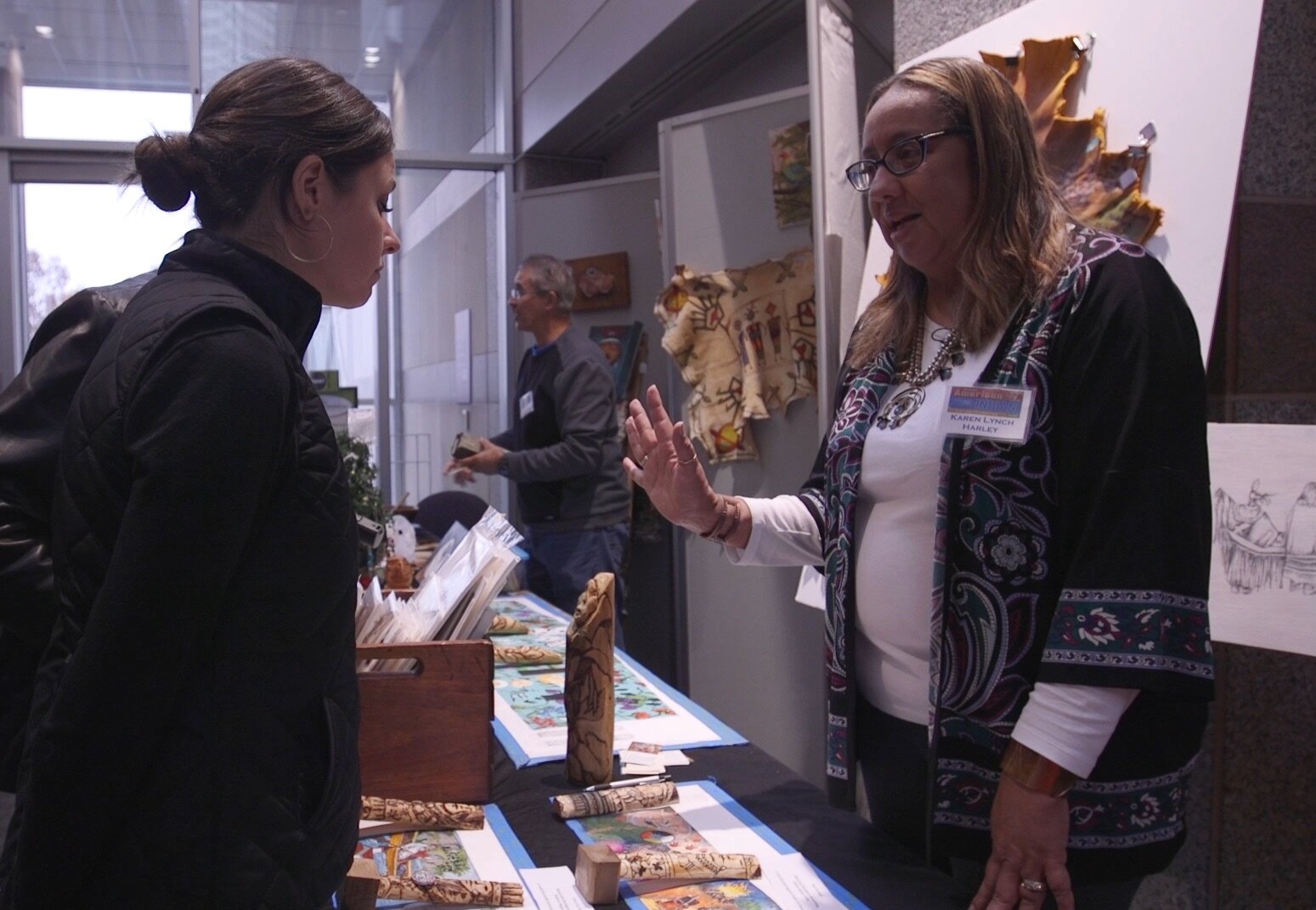  Here artist Karen Harley shares information about the renderings with an attendee of the 24th Annual American Indian Heritage Celebration.  Photo Courtesy of Brooks Bennett  