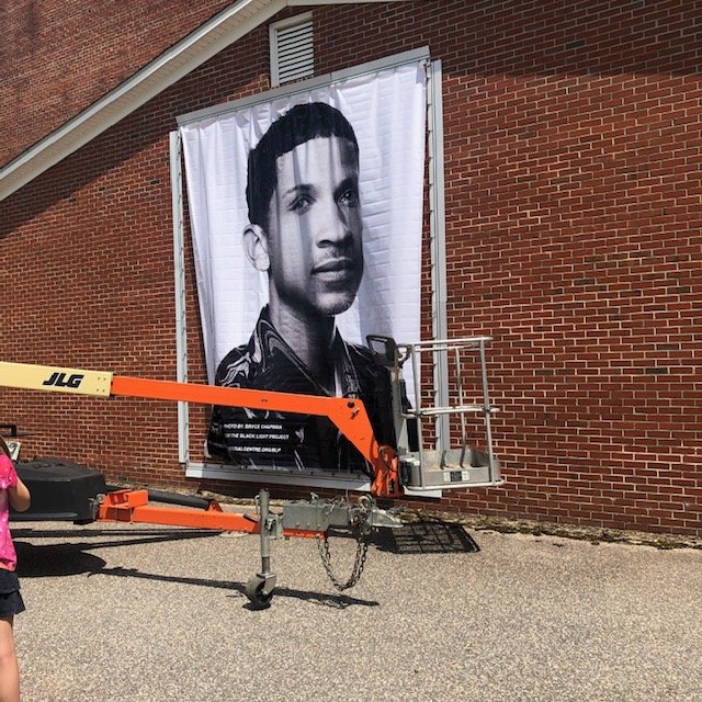  Here the banner portrait of JoSeth Bocook is being installed at the R.M. Wilson Gymnasium.  Photo courtesy of Alicyn Wiedrich  