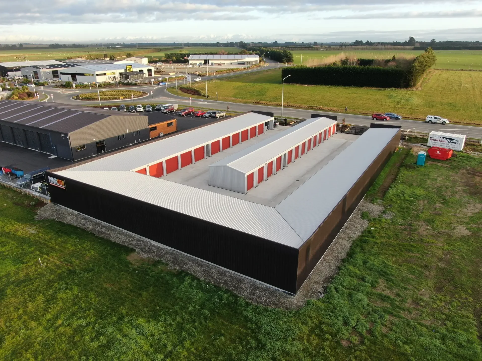 Historical aerial view of Storage4Less in Rolleston, showing rows of storage units with red roller doors and concrete driveways.