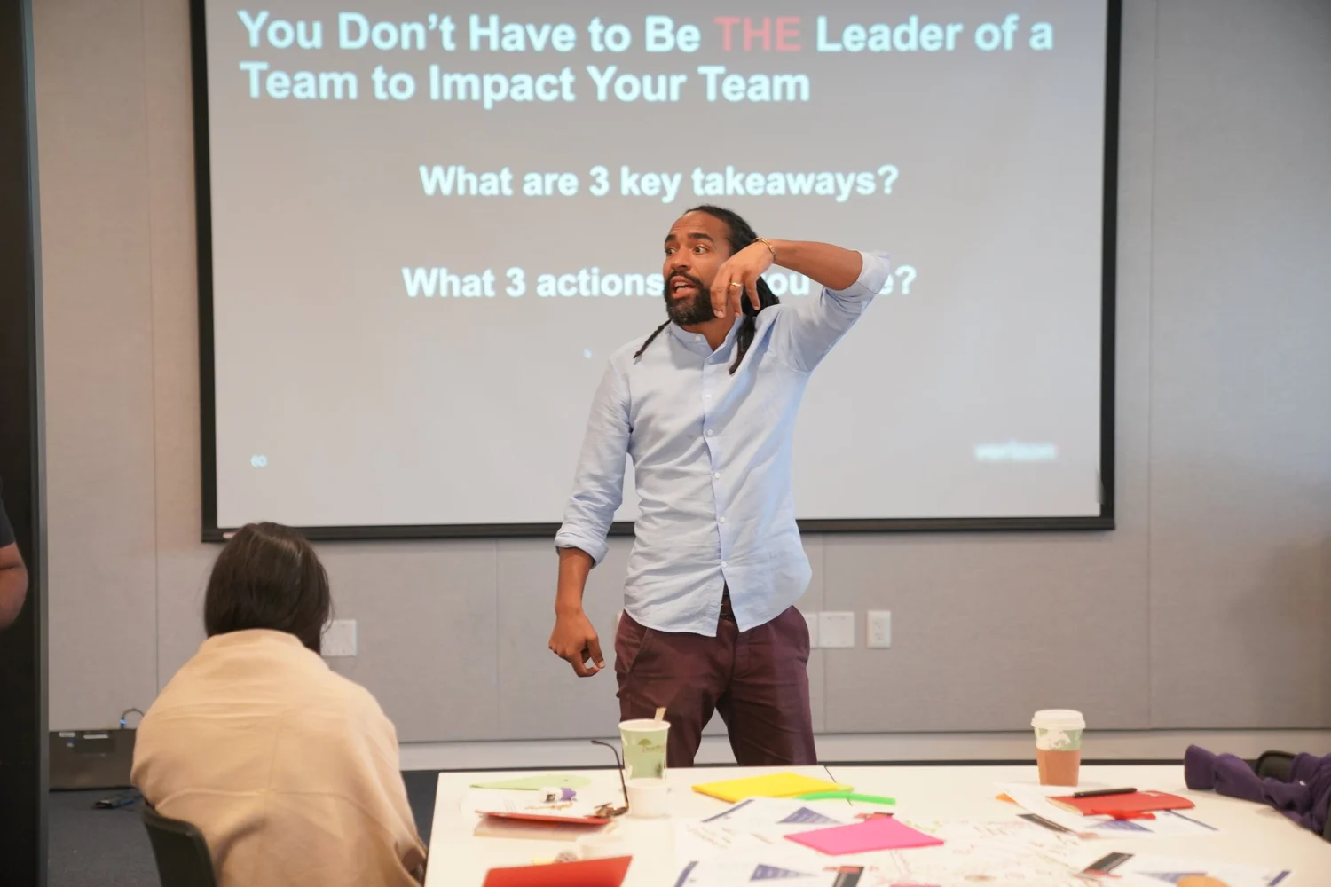 Didier Sylvain teaching a leadership session, a slide reading You Don’t Have to Be THE Leader of a Team to Impact Your Team projected behind him