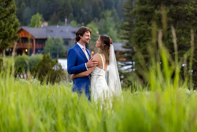 Newly weds on the hill behind Rainbow Ranch Wedding Venue near Big Sky Montana. The couple is gazing into each others eyes, with the venue in the background.