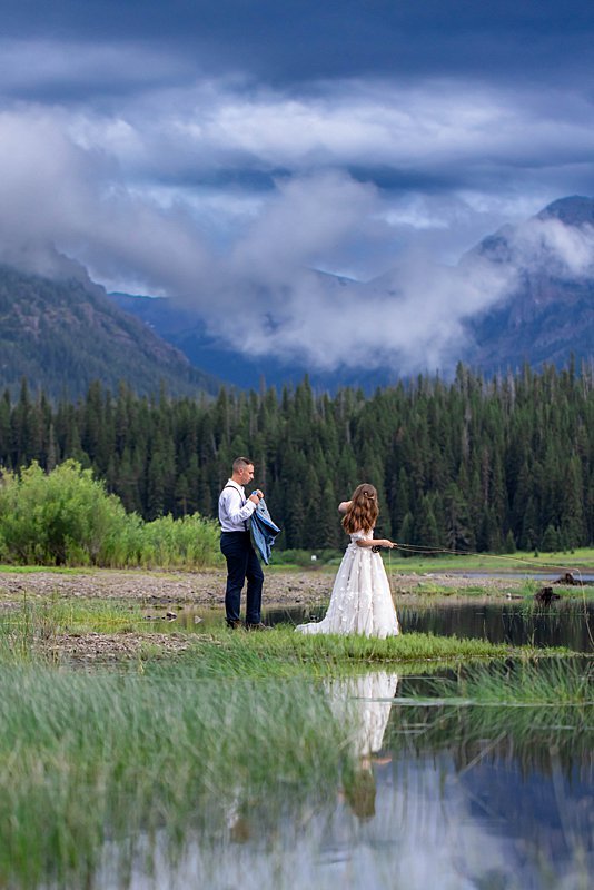 Groom offering his new wife a jacket as she flyfished among the mountains of Montana.
