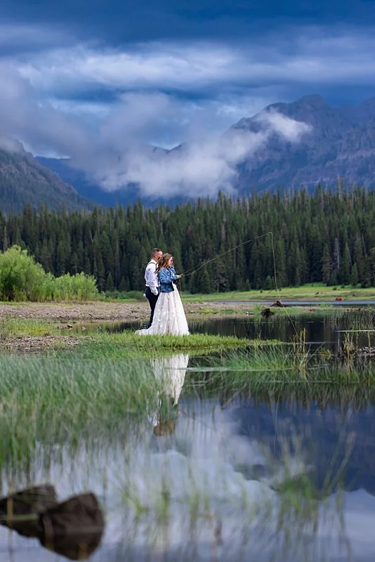 A bride and groom flyfishing under a moody mountain sky in Montana.