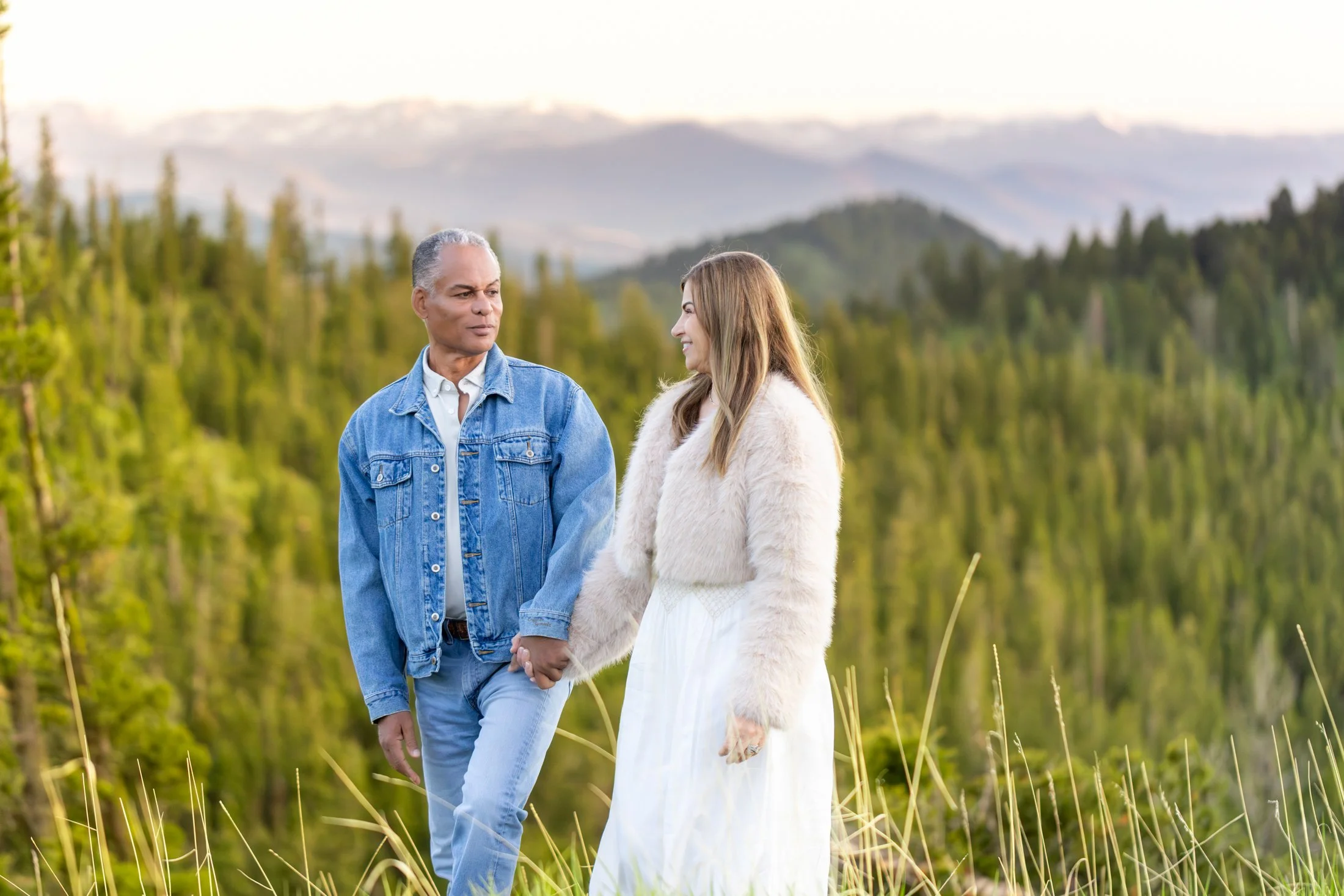 A beautiful couple walks through the high mountain environment, enjoying each other - focused on connecting and loving instead of posing an staring at the camera.