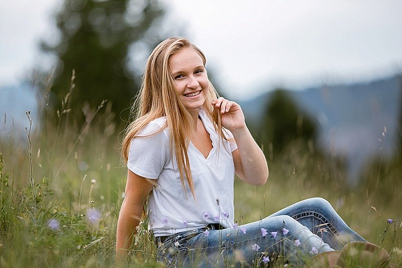 A senior girl from Bozeman Montana in a field of wildflowers, smiling and relaxing.