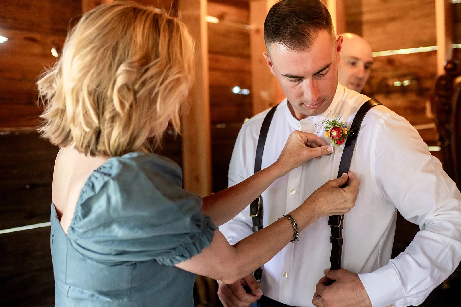 Mother pinning boutonniere on her son on his wedding day.