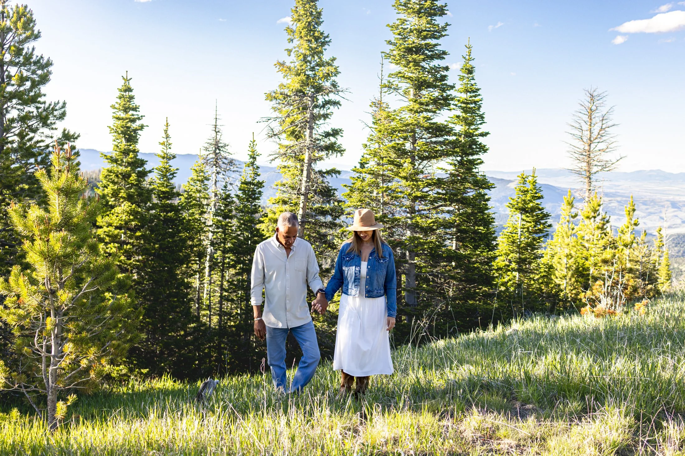 A stunning couple at their Montana Engagement Session, walks through a mountain meadow for amazing time together.