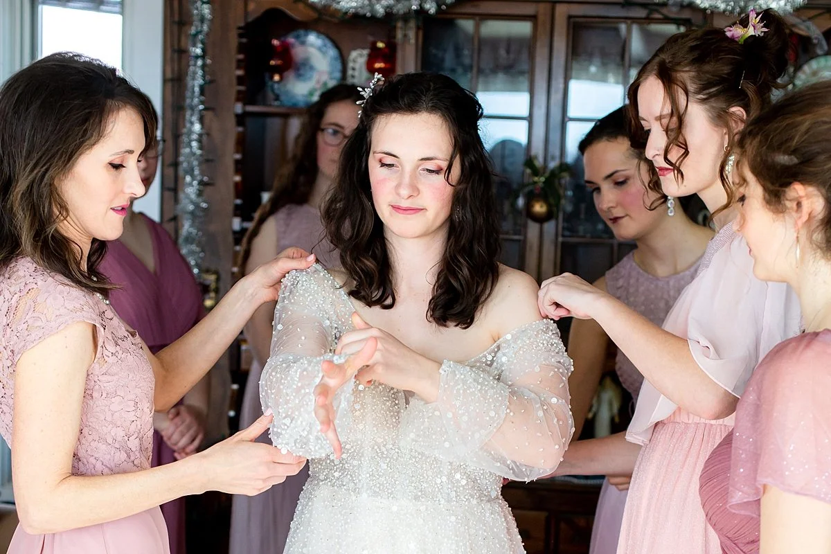 A group of bridesmaids helping a bride get her dress on and adjusted for her wedding near Bozeman Montana