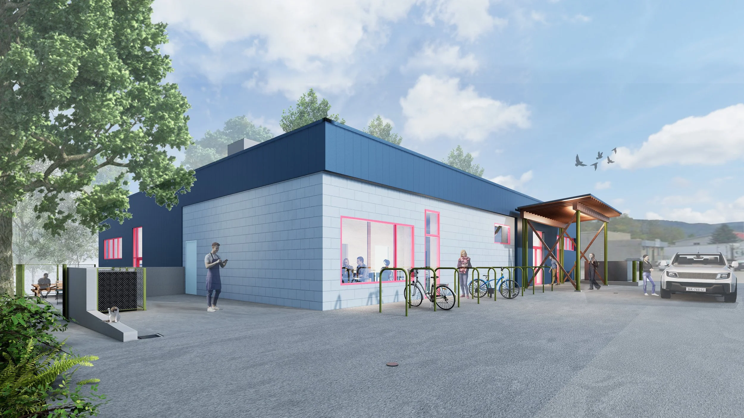 A modern building with large windows and a sloped roof, surrounded by trees and a parking lot, with people walking, biking, and sitting outside on benches.