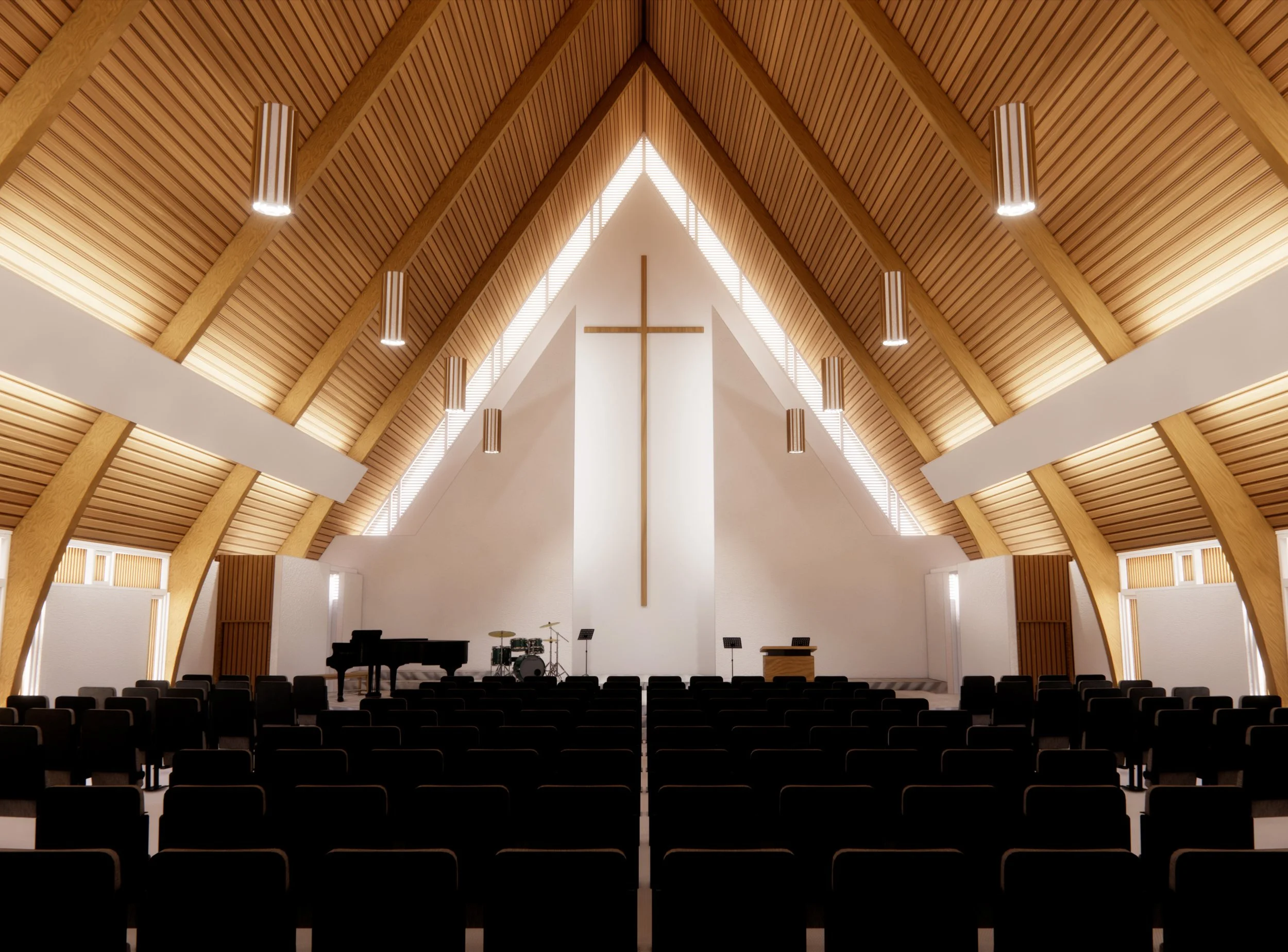 Interior of a modern church or chapel with a high, vaulted wooden ceiling, a central cross at the front, and rows of dark chairs, illuminated by hanging pendant lights.