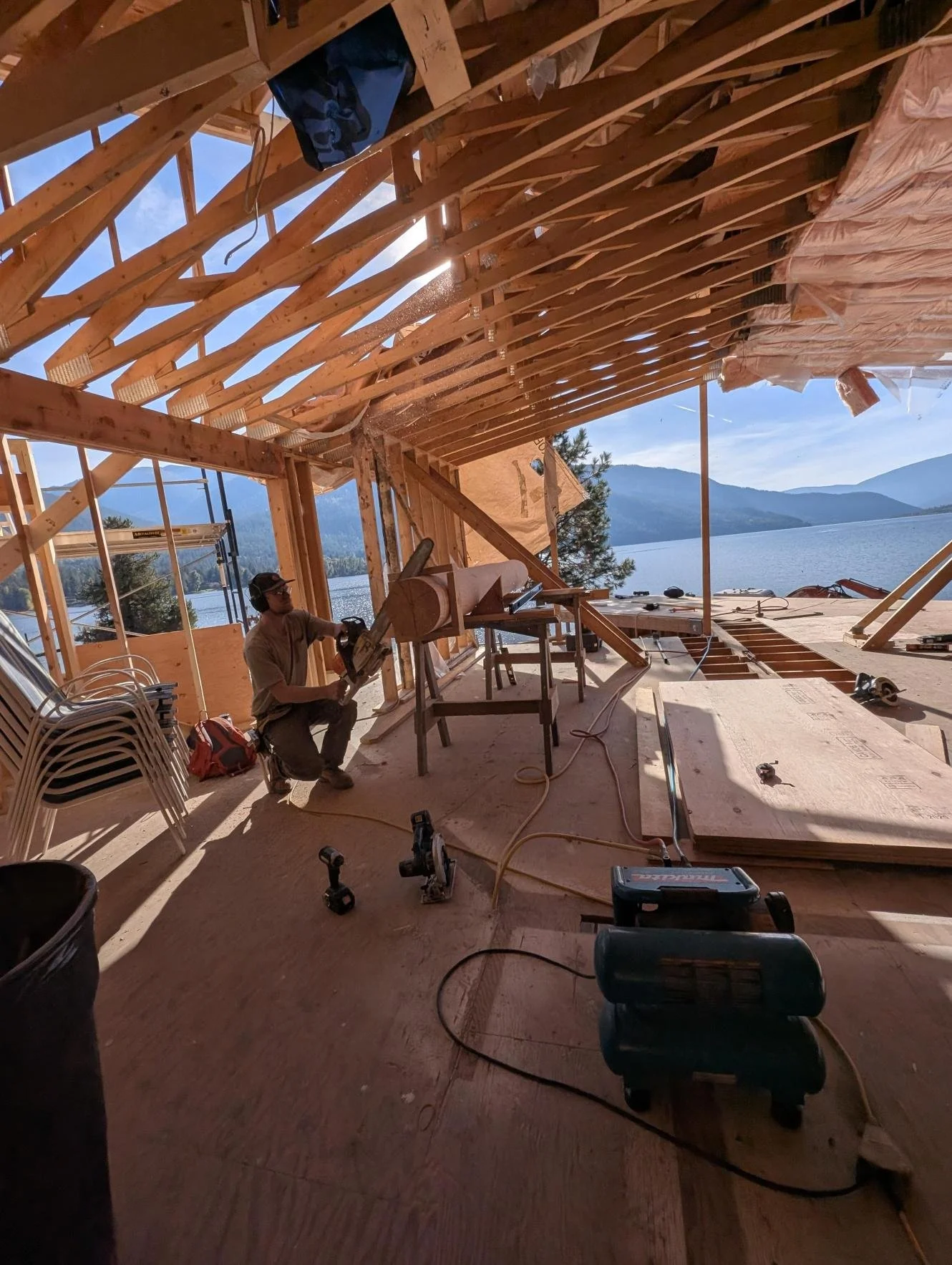 carpenter cutting wood with mountains and a lake in the rear background