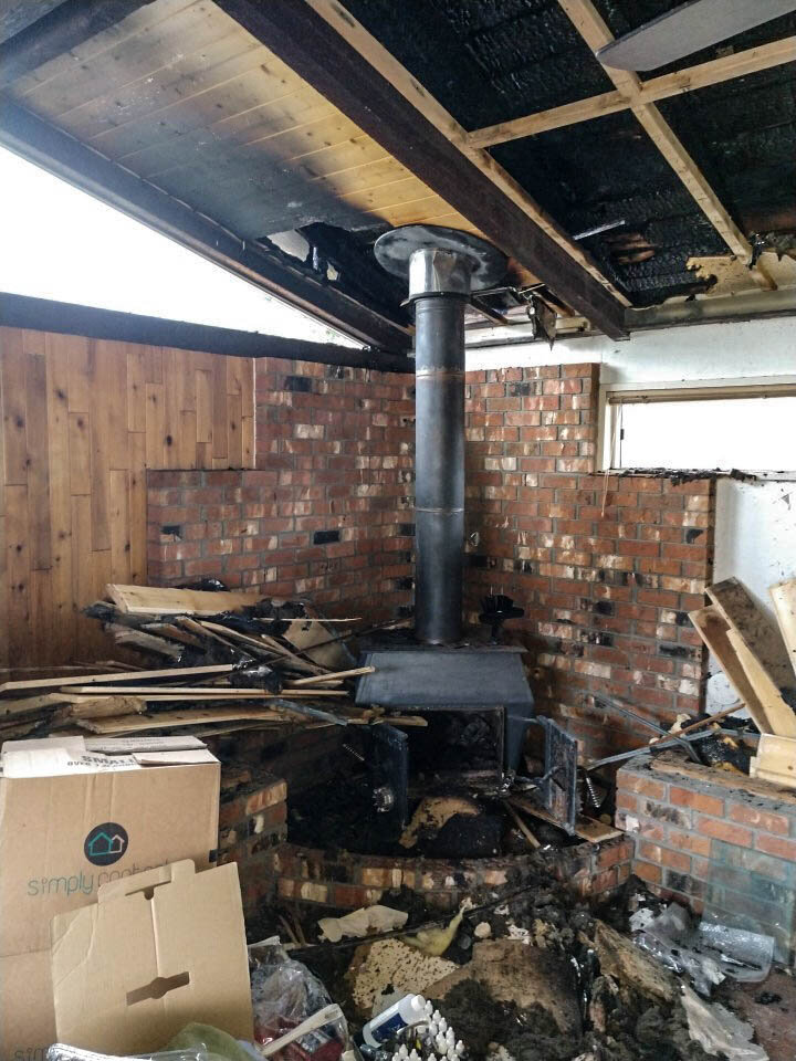 An accumulation of combustible materials above the freestanding stove caused severe fire damage to this throughout the home.