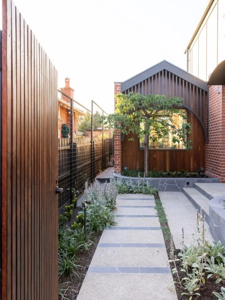 Granite paving and rich timber detailing define the entrance to this rear garden with the perfect balance of structure and warmth 

Featuring Thymus pseudolanuginosus between the pavers, Stachys byzantina and Liriope &lsquo;Amethyst&rsquo; soon to fi