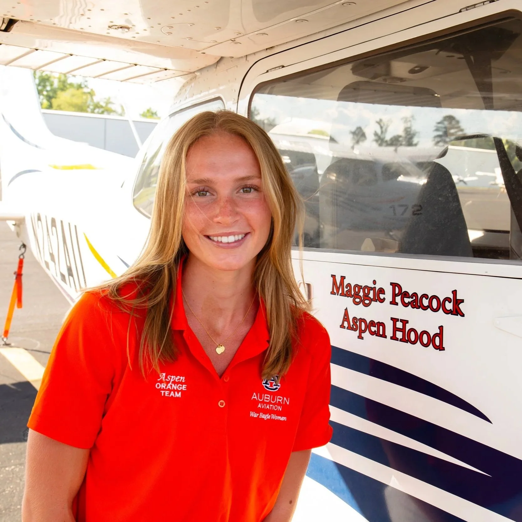 Aspen Hood smiling at the camera while standing next to her name on plane 64