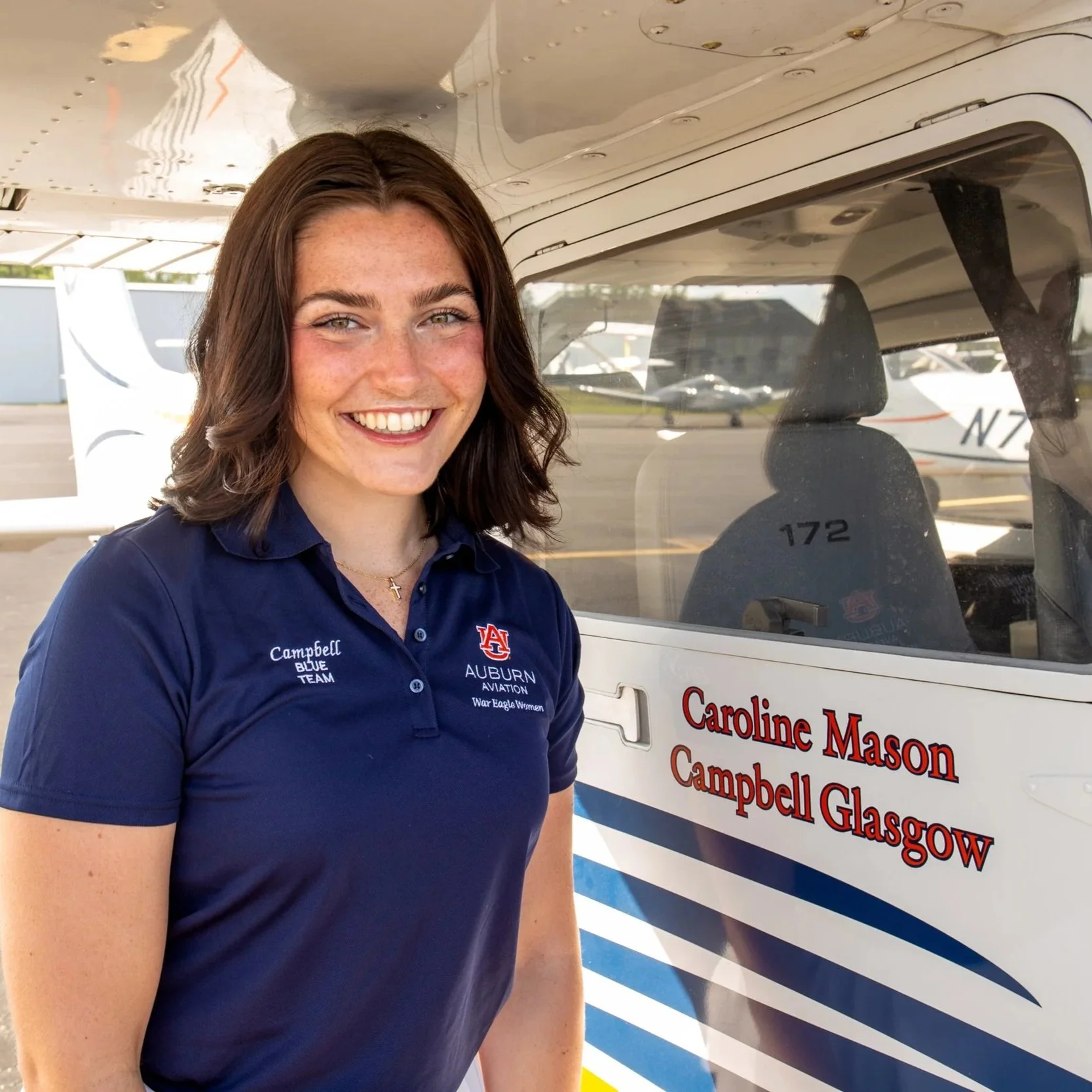 Campbell Glasgow smiling at the camera while standing next to her name on plane 63.