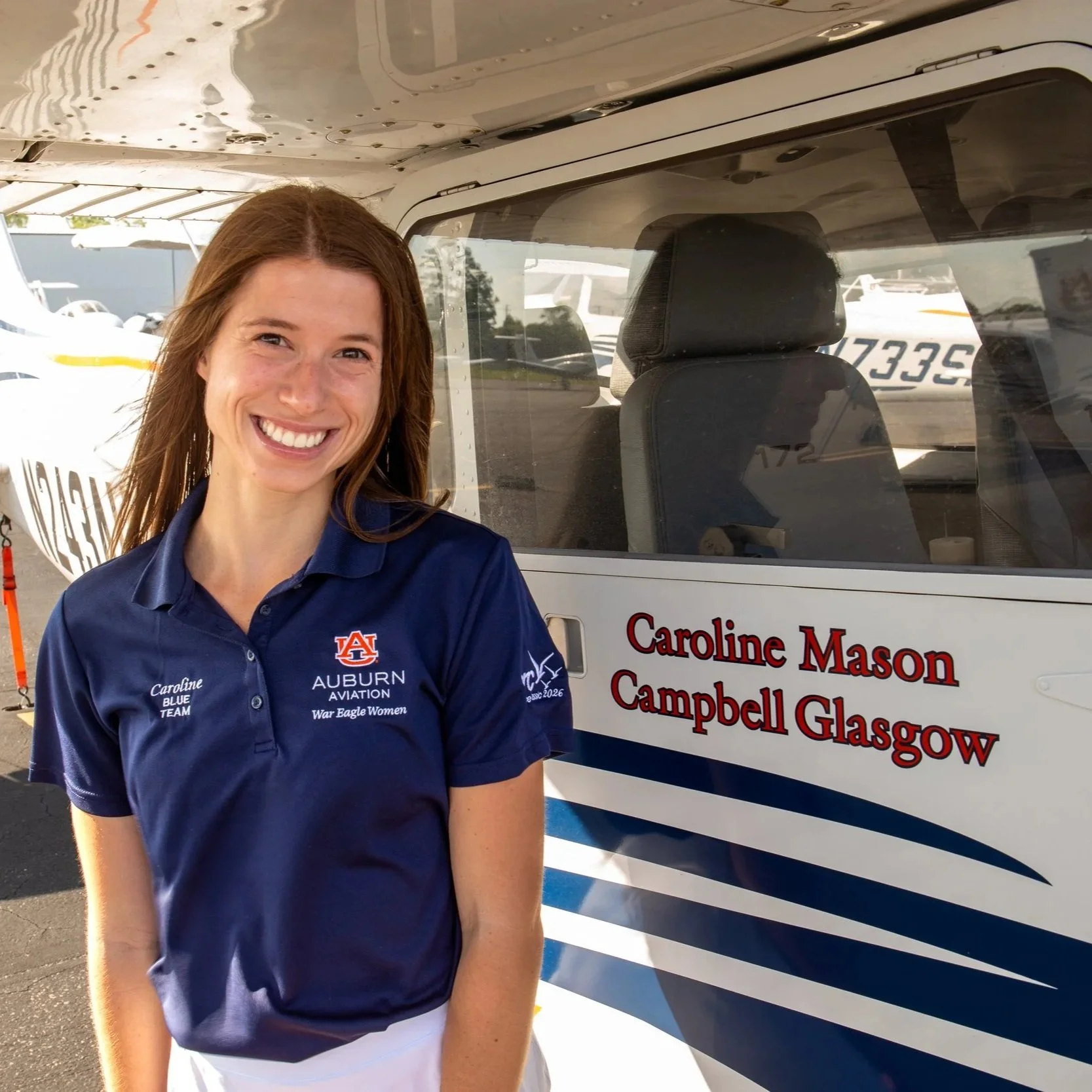 Caroline Mason smiling at camera while standing next to plane 63.