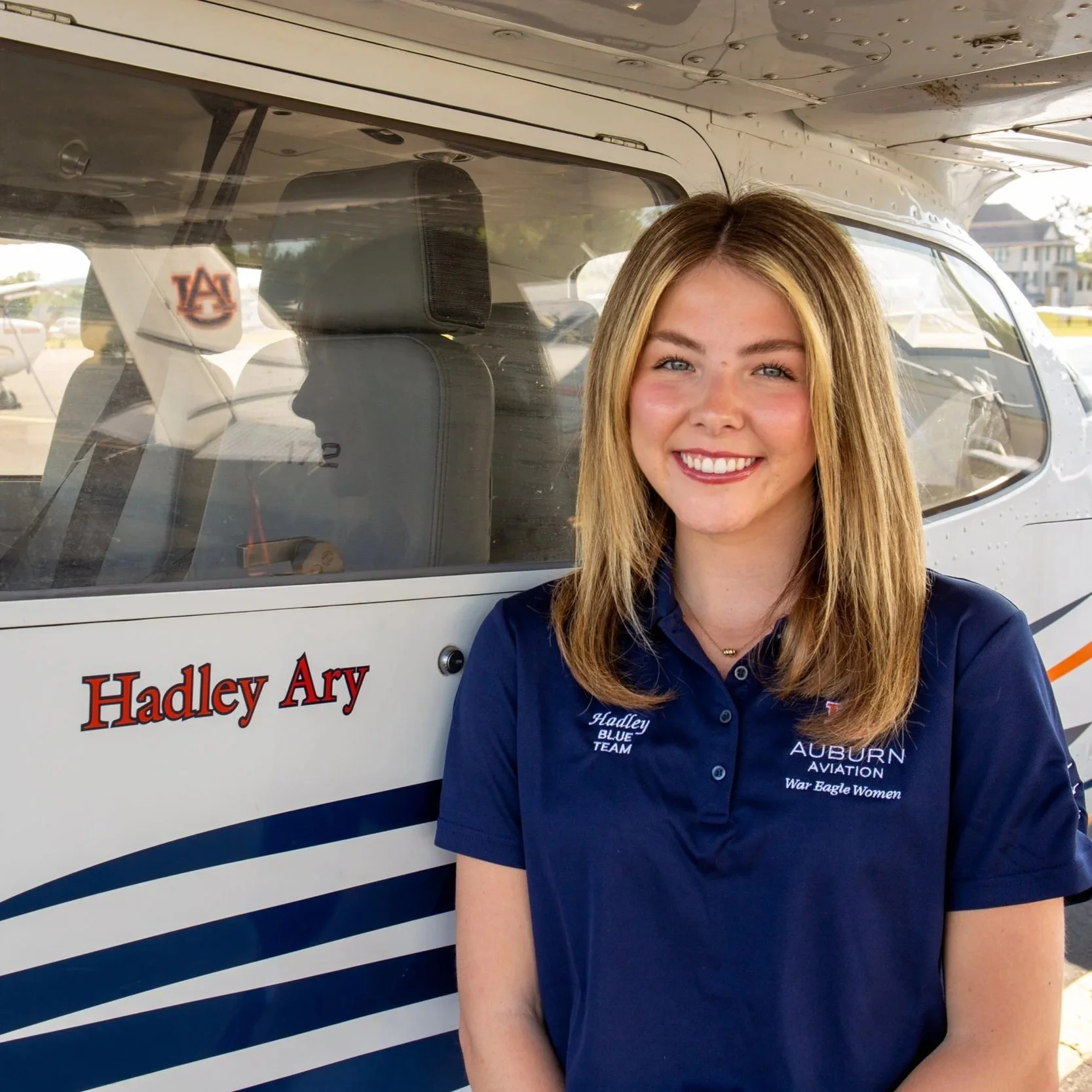 Haldey Ary smiling at camera while standing next to her name on plane 63