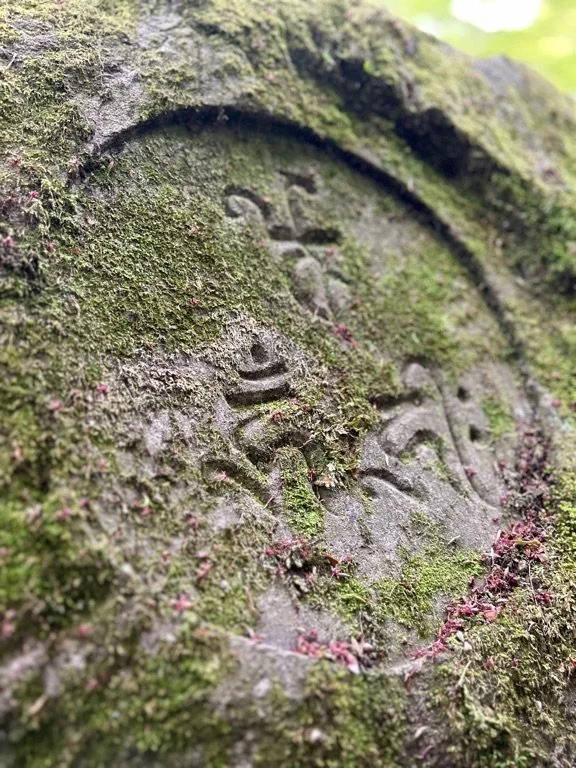 Close-up of an old, moss-covered stone with carved symbols on its surface.