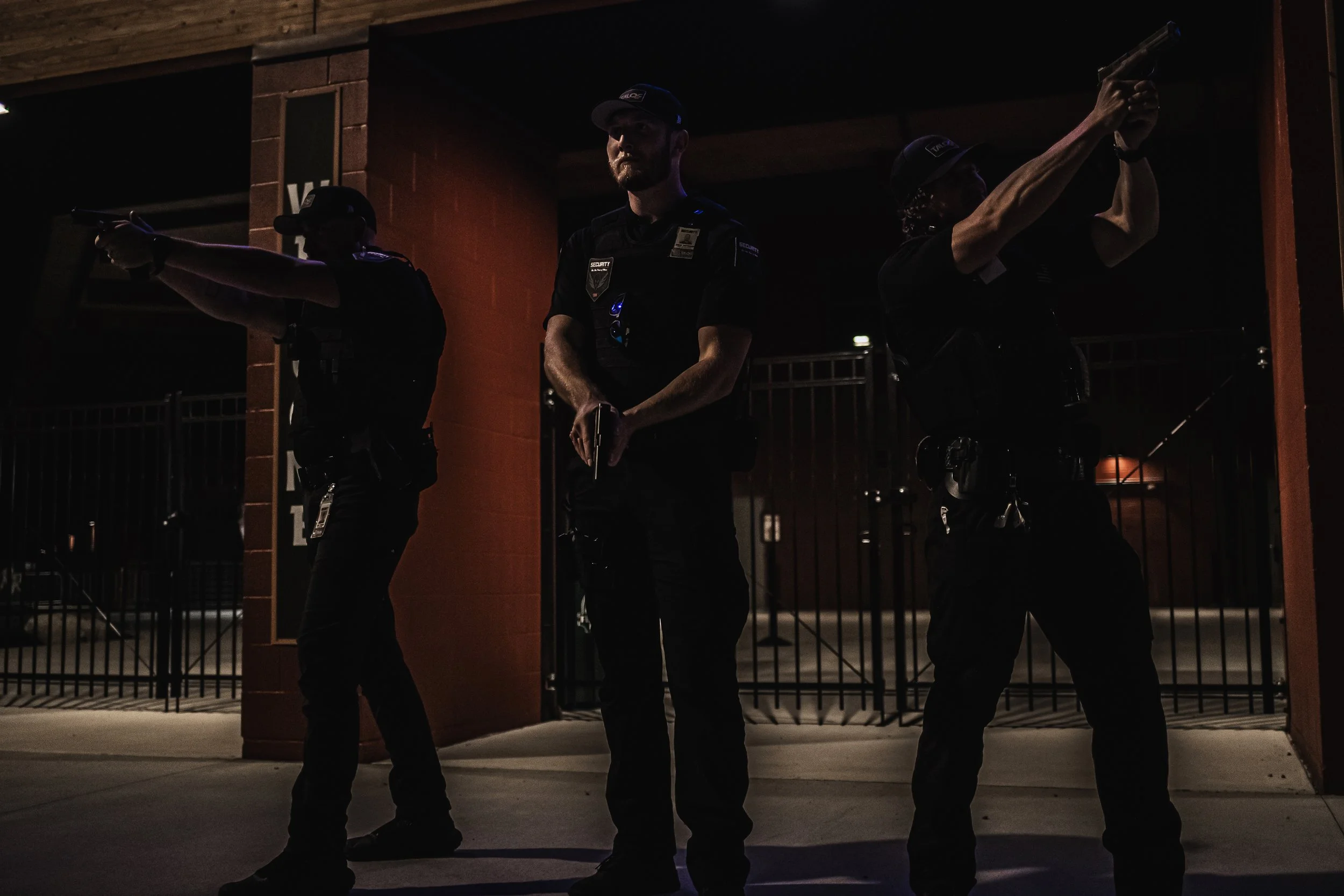 Three police officers holding guns in a dark, outdoor setting at night.